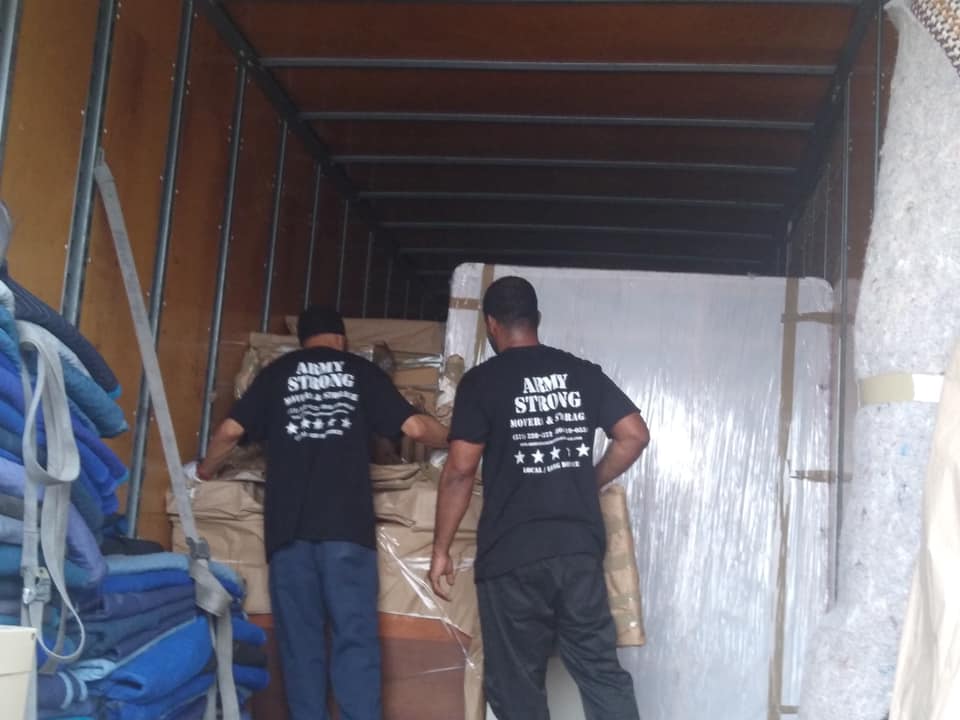 Two Army Strong movers loading a mattress into the truck