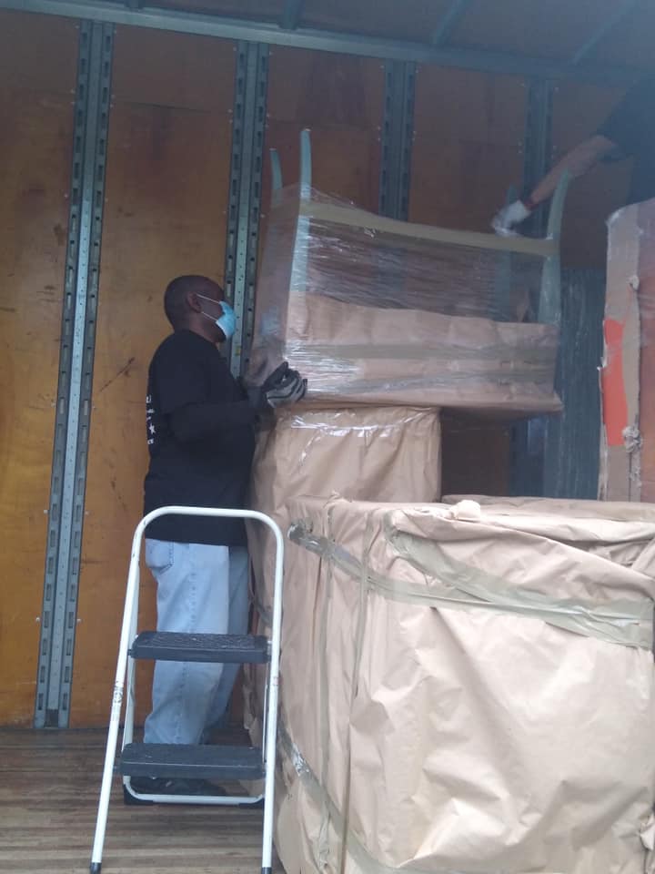 Army Strong mover wrapping a wooden chair in protective paper inside the truck